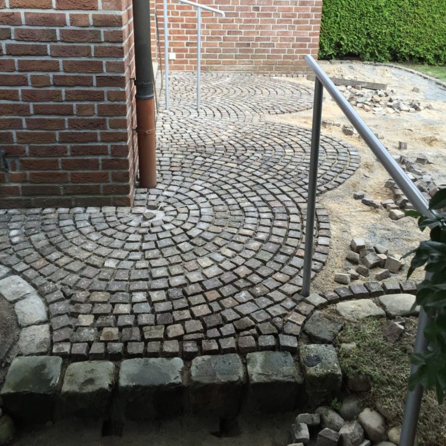 Kreisförmiges Pflastermuster mit Randsteinen an einer Hauswand