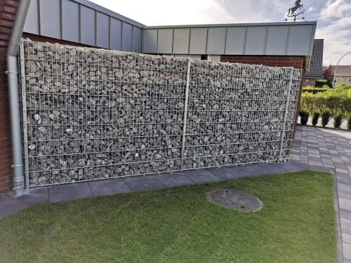 Große Gabionenwand als Grundstücksabgrenzung mit Pflasterweg