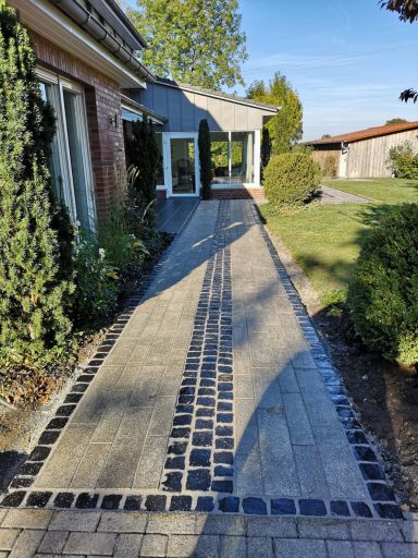 Moderner Gehweg mit rechteckigem Pflaster und Natursteinstreifen