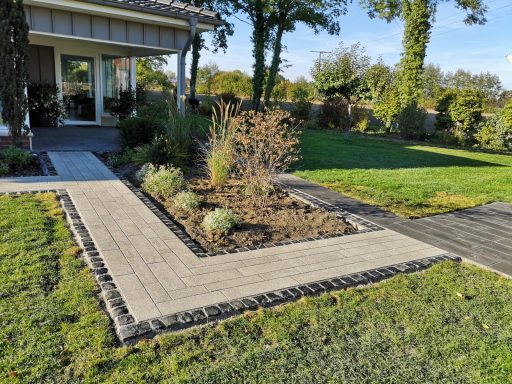Gartenweg mit Pflastersteinen und Beetflächen